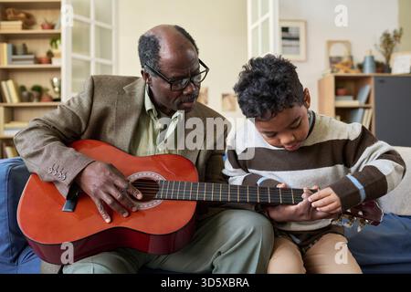 Senior Black Man Unterrichtet Jungen, Der Zusammen Gitarre Spielt Stockfoto