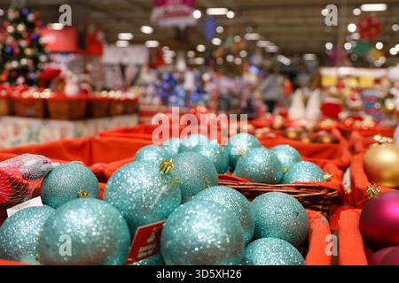 Weihnachtsspielzeug, türkisfarbene Kugeln in Körben auf verschwommenem festlichem Lichthintergrund. Neujahrsdekoration in einem Supermarkt Stockfoto