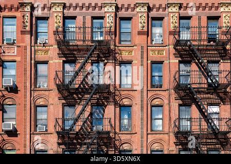 Nahaufnahme eines typischen Harlem Wohngebäudes mit roten Backsteinen und dekorativen Details über den Fenstern. Stockfoto