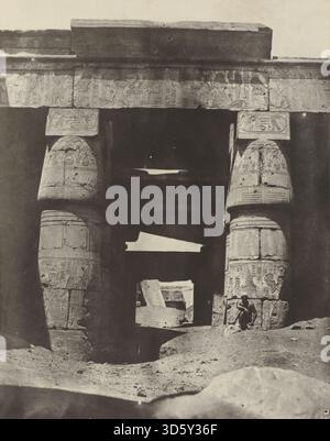 Dieses Werk von Maxime du Camp aus dem Jahr 1850 zeigt den Portikus des Tempels der Khons in Karnak in Theben, mit architektonischen Säulen, Hieroglypheninschriften, Steinmauern und umgebenden Tempelstrukturen in detaillierter Perspektive. Stockfoto