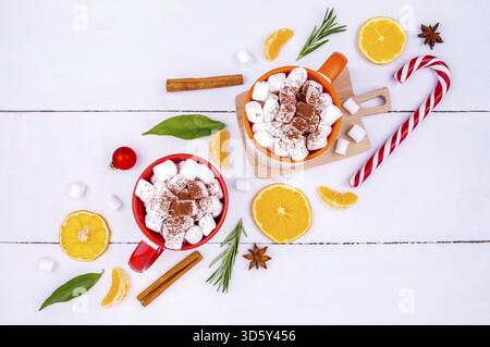 Weihnachtliche Kulisse mit zwei Tassen Kakao und Marschmalchen, Mandarinen-Keilen, frischen Rosmarinzweigen und festlichem Dekor Stockfoto