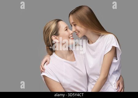 Mutter und Tochter Atelier Porträt. Grauer Hintergrund. Lächelnde Menschen. Zwei weibliche Familienmitglieder. Freunde umarmen sich. Kommunikation für Erwachsene. Kopierraum. Schließen Sie nr Stockfoto