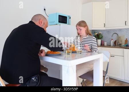 Paare, die Pasta essen und sich in einer gemütlichen Küche unterhalten. Stockfoto