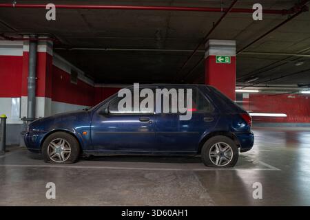 Verlassenes blaues Auto mit Platten Reifen in der Tiefgarage Stockfoto