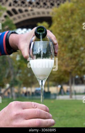 Ausgießen und Trinken von französischem Sekt aus Tulpenglas mit Blick auf die Straßen, Gebäude und Türme von Paris, Hochzeitsveranstaltung in Paris Stockfoto