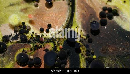 Ölblasen. Glitzerfarbe. Defokussierte gelbe orange Farbe funkelnde dunkelschwarze Textur Mischung Wasser schwimmt auf abstraktem Bokeh-Kunsthintergrund. Stockfoto
