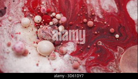 Acrylblasen. Lacköl Wasser. Defokussierte rote weiße rosafarbene Farbe vibrierende Glitzertextur Mischung Flüssigkeitsfluss Spill auf abstraktem Hintergrund. Stockfoto