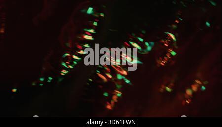 Linse für Unschärfe-Licht. Folie leuchtet. Rot-grünes Neon farbenfrohe Helligkeit auf dunkelschwarzem Hintergrund. Abstrakter spektrumoptischer Effekt. Stockfoto