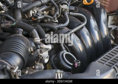 Nahaufnahme eines leistungsstarken Motormotors mit Autotechnologie zur Reparatur. Komplexes neues Kraftfahrzeug unter der Motorhaube mit schwarzen Kunststoff- und Metallteilen Stockfoto