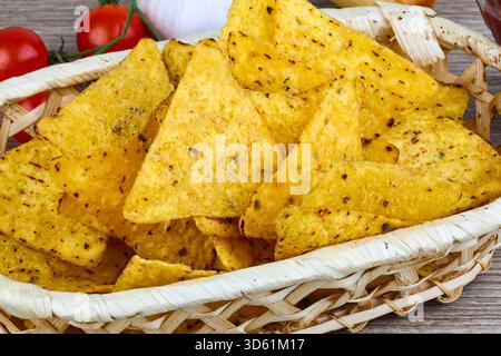 Aus nächster Nähe ein Korb voller goldener, dreieckiger Tortilla-Chips, gewürzt mit Kräutern und Gewürzen. Stockfoto