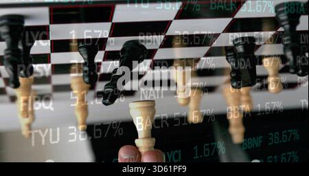Halten Sie die Hand, heben Sie den Elfenbeinkönig zwischen den Fingern an Bord mit reflektierten Stücken, mit Market Ticker Stockfoto