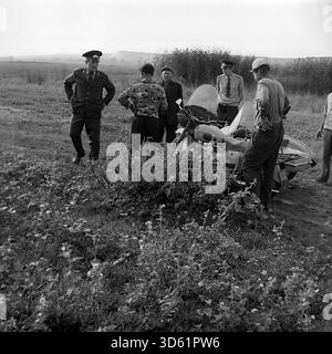 UdSSR, Ukrainische SSR, Slavyanogorsk (Svyatogorsk), 1970er Jahre Eine freimütige Szene in einem Feld in der Nähe des Resorts mit sowjetischen Militsiya-Offizieren und Anwohnern. Eine Gruppe von Männern versammelt sich mit einem Beiwagen um ein Motorrad. Ein Offizier schreibt ein Dokument, während ein anderer bereit ist. Die Zivilisten in lässigen Kleidern reden und rauchen; ein Mann lächelt in die Kamera. Der Hintergrund zeigt Schilf und ferne Hügel. Dieses archivierte Schwarzweiß-Foto zeigt ein Stück ländliches Leben im friedlichen Donbass. Stockfoto