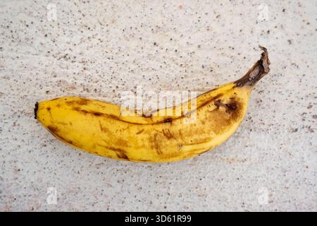 Überreife Banane auf gesprenkelter Steinoberfläche Stockfoto