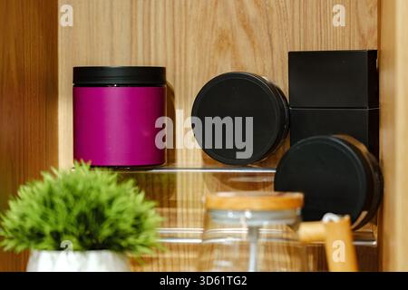 Farbenfrohe Gläser und Behälter, ordentlich auf einem Holzregal in gemütlicher Umgebung angeordnet Stockfoto