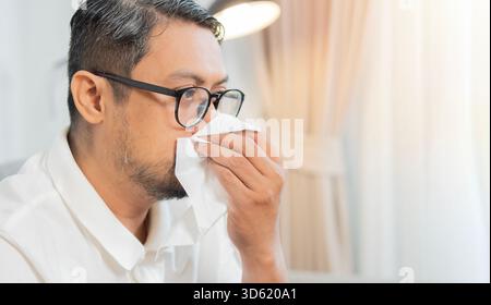 Reifer Mann, der unter trockenem Husten, Gesundheitsproblem der Grippe, Erkältung oder medizinischem Virus leidet. Blasnase durch Gewebe. Seitenansicht, Kopierraum. Stockfoto