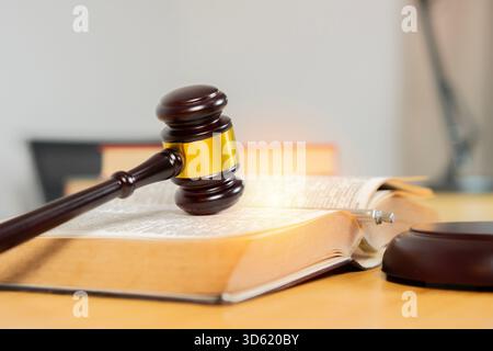 Richter Hammer und Buch auf Holztisch im Zimmer. Symbolisiert das Konzept von Gerechtigkeit und Rechtshoheit. Selektiver Fokus. Stockfoto