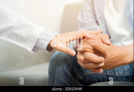Betreuer, Arzt hält die Hand ihres Patienten und zeigt Freundlichkeit während einer Untersuchung im Krankenhauszimmer. Nahaufnahme. Stockfoto