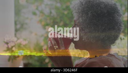 Sie schlürft eine ältere afroamerikanische Frau in Rosen-Top auf der Veranda, hält Becher, Sonnenuntergang-Overlay, Kopierraum Stockfoto