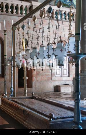 Ein Zimmer mit einem Holztisch und einem Holzsarg. Der Tisch ist mit Kerzen und Lampen bedeckt Stockfoto