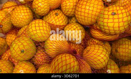Nahaufnahme frischer Mandarinen in roter Netzverpackung in einem Marktumfeld. Stockfoto