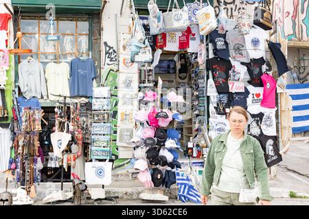 Athen, Griechenland - 15. Mai 2024: Souvenirladen und Frau, die im Touristenviertel vorbeiläuft Stockfoto