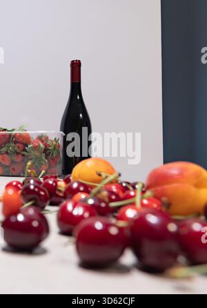 Horizontale Nahaufnahme von Rotwein und einer Vielzahl von frischen Früchten (Trauben, Beeren) auf einem Tisch mit einem einfachen Hintergrund für den Kopierraum Stockfoto