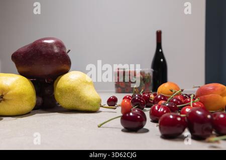 Horizontale Nahaufnahme von Rotwein und einer Vielzahl von frischen Früchten (Trauben, Beeren) auf einem Tisch mit einem einfachen Hintergrund für den Kopierraum Stockfoto