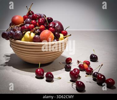 Vertikale Nahaufnahme von frischen, lebendigen Zitrusfrüchten (Orangen und Zitronen), angeordnet mit einem Glaskrug auf einer hellen Holzoberfläche. Fokus auf Gesundheit Stockfoto