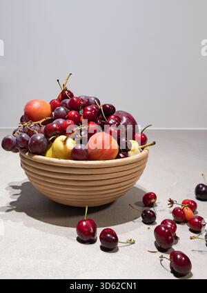 Vertikale Nahaufnahme von frischen, lebendigen Zitrusfrüchten (Orangen und Zitronen), angeordnet mit einem Glaskrug auf einer hellen Holzoberfläche. Fokus auf Gesundheit Stockfoto