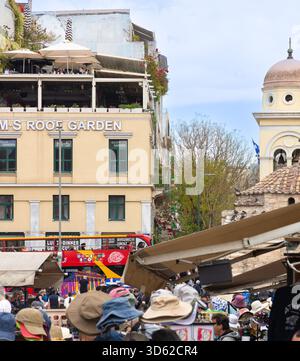 Athen, Griechenland - 15. Mai 2024: Touristen und Einheimische auf einem belebten Platz mit historischer Kirche und Sightseeing Bus Stockfoto