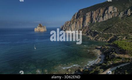 Aus der Vogelperspektive auf die berühmte Felsformation Pan di Zucchero, die aus dem türkisfarbenen Meer steigt, eingerahmt von zerklüfteten Klippen und üppigem Grün, Masua, Sardinien, IT Stockfoto