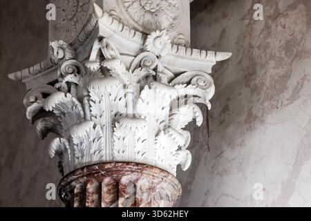 Auf einem roten Marmorschacht befindet sich eine fein detaillierte korinthische Hauptstadt mit Akanthusblättern und Rollarbeiten. Dieses klassische architektonische Detail zeigt Stockfoto