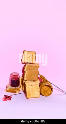 Hoher Stapel Toast mit Marmeladenglas und Erdnussbutter auf weichem rosa Hintergrund Stockfoto