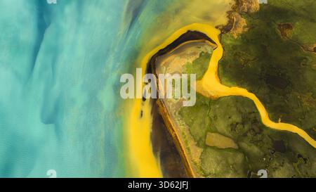Aus der Vogelperspektive auf türkisfarbenes Wasser treffen auf leuchtende gelbe Bäche inmitten der zerklüfteten grünen Landschaft, die eine surreale und atemberaubende aussicht auf Landmannalau schaffen Stockfoto