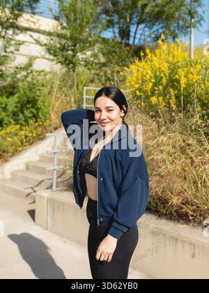 Eine junge Frau posiert während eines Spaziergangs im Park an einem sonnigen Morgen in Saragossa, Spanien Stockfoto