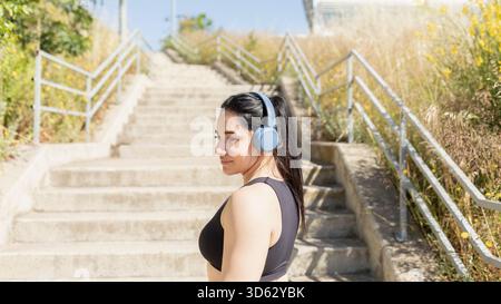 Eine Frau hört Musik, während sie mentalisiert, bevor sie ein Rennen durch Treppensteigen in Saragossa, Spanien, startet Stockfoto