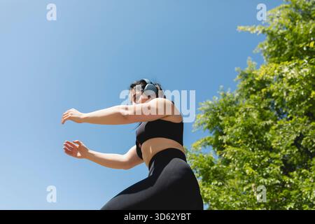 Eine Frau führt Arme- und Beinübungen für einen sonnigen Tag in Saragossa, Spanien, durch Stockfoto