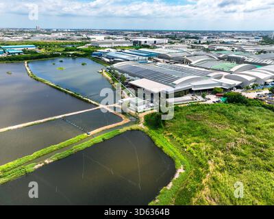 Ein moderner Industriewerkkomplex mit Solarpaneelen, die auf den Dächern des Lagers neben Abwasseraufbereitungsteichen installiert sind. Nachhaltige Energie Stockfoto