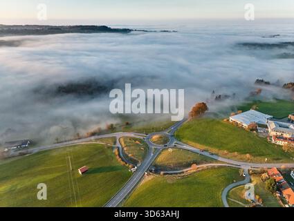 Luftaufnahme des Kreisverkehrs an der B 308 bei Sonnenuntergang mit Nebelflecken in Weiler-Simmerberg, Allgaeu, Bayern, Deutschland Stockfoto