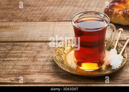 Türkischer schwarzer Tee. Eine Glasschale türkischer schwarzer Tee und knuspriger türkischer traditioneller Bagel auf altem Rustick-Hintergrund. Frühstücksgebäck-Konzept. Traditionelles türkisches Heißgetränk. Stockfoto