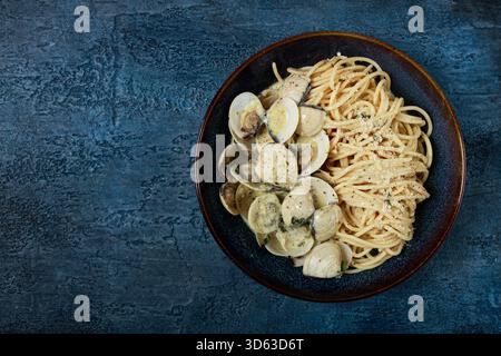 Spaghetti mit Vongole Venusmuscheln, in Sahnesauce, Carbonara, auf dunkelblauem Hintergrund, hausgemacht, Draufsicht, keine Leute, Stockfoto