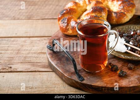Türkischer schwarzer Tee. Eine Glasschale türkischer schwarzer Tee und knuspriger türkischer traditioneller Bagel auf altem Rustick-Hintergrund. Frühstücksgebäck-Konzept. Traditionelles türkisches Heißgetränk. Stockfoto