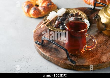 Türkischer schwarzer Tee. Eine Glasschale türkischer schwarzer Tee und knuspriger türkischer traditioneller Bagel auf grauem Betontischhintergrund. Frühstücksgebäck-Konzept. Traditionelles türkisches Heißgetränk. Stockfoto