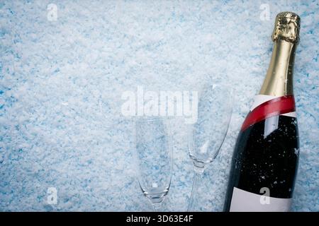Weihnachts- und Neujahrsfeiern, Festtage, elegante Partys und saisonale Veranstaltungen. Eine Champagnerflasche liegt auf Schnee neben zwei leeren champa Stockfoto