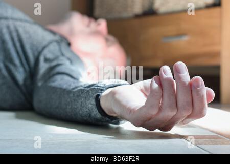 Mann, der zu Hause auf dem Boden liegt, Epilepsie, Bewusstlosigkeit, Ohnmacht, Schlaganfall, Unfall oder anderes Gesundheitsproblem, Gesundheitswesen und medizinisches Konzept Stockfoto