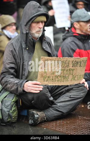 EDINBURGH, SCHOTTLAND: 18. November 2025: Demonstranten sitzen mit Plakat. Am 18. November 2025 versammelten sich Demonstranten vor dem Queen Elizabeth House in Edinburgh als Teil der landesweiten „Lift the Ban“-Aktionen, die die britische Regierung gegen das Verbot der Palästinensischen Aktion als terroristische Organisation anfechten. Demonstranten sitzen still und halten Schilder mit der Aufschrift „Ich bin gegen Völkermord. Ich unterstütze die Palästinensische Aktion“, während Mitglieder der schottischen palästinensischen Solidaritätskampagne T-Shirts mit der Aufschrift „Völkermord in Palästina“ tragen. Zeit, Maßnahmen zu ergreifen.“ Quelle: Eastern Goodwin Media/Alamy Live News Stockfoto