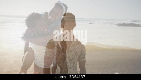 Ein stehender Mann in der Mitte mit Blumenhemd am Strand, ein Paar mit gestreiftem Oberteil und Haarreif Stockfoto