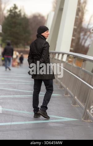 40-jähriger Mann mit Hut und Trenchcoat. 40-jähriger Mann, der mit Hut und Trenchcoat läuft. Lächelnder Mann mittleren Alters. Herbstmode für Herren. Stockfoto