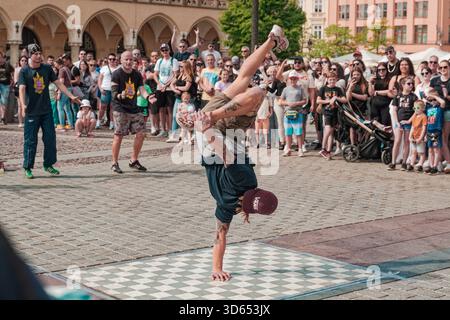 Breakdancer von Kraków B-Boy Familia spielt einen einhändigen Handstand während einer Straßenshow auf dem Hauptmarkt. Stockfoto