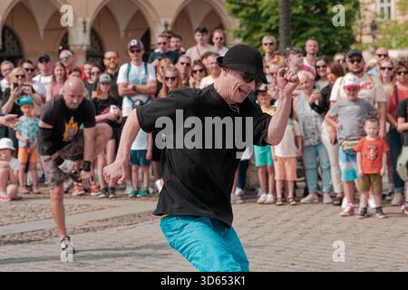 Breakdancer spielt während einer Straßenshow am Main Market Square, umgeben von einer großen Menschenmenge, tatkräftige Fußarbeit. Stockfoto